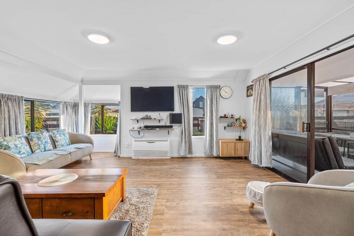 A spacious living room with a sofa, a coffee table, and a TV mounted on the wall.