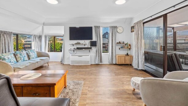 Un salon spacieux avec un canapé, une table basse et un téléviseur fixé au mur.