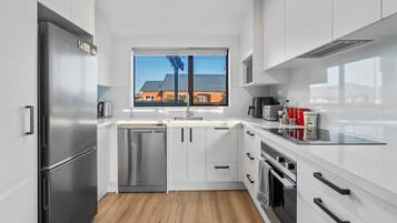 Een moderne keuken met roestvrijstalen apparatuur, witte kasten en een raam met uitzicht op gebouwen.
