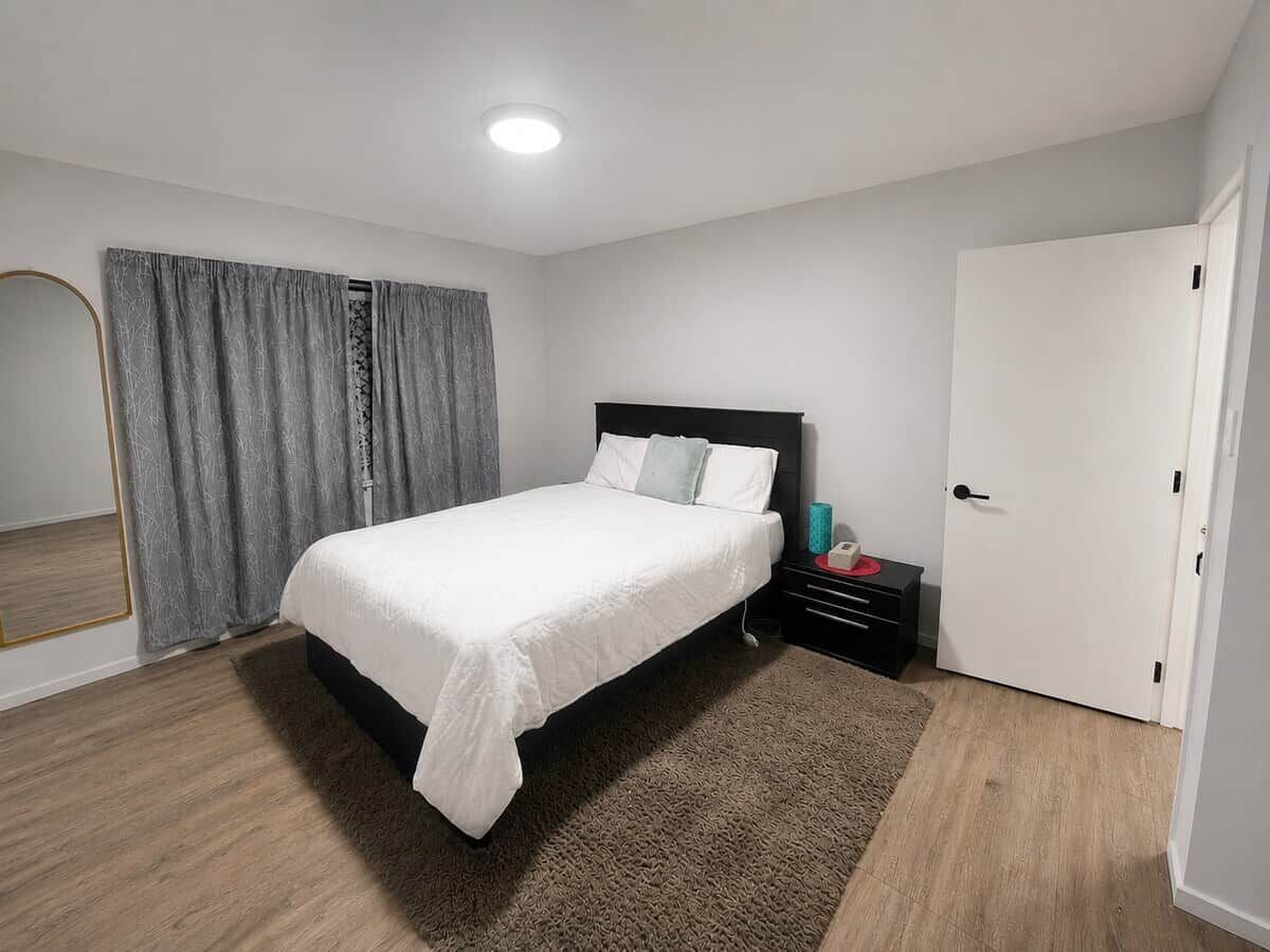 A modern bedroom with a bed, bedside table, and a door.