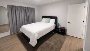 Une chambre à coucher moderne avec un lit, une table de chevet et une porte.