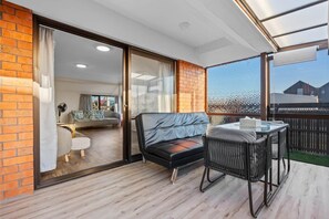 A balcony with a sofa, a table, and chairs, and a view of a building in the background.