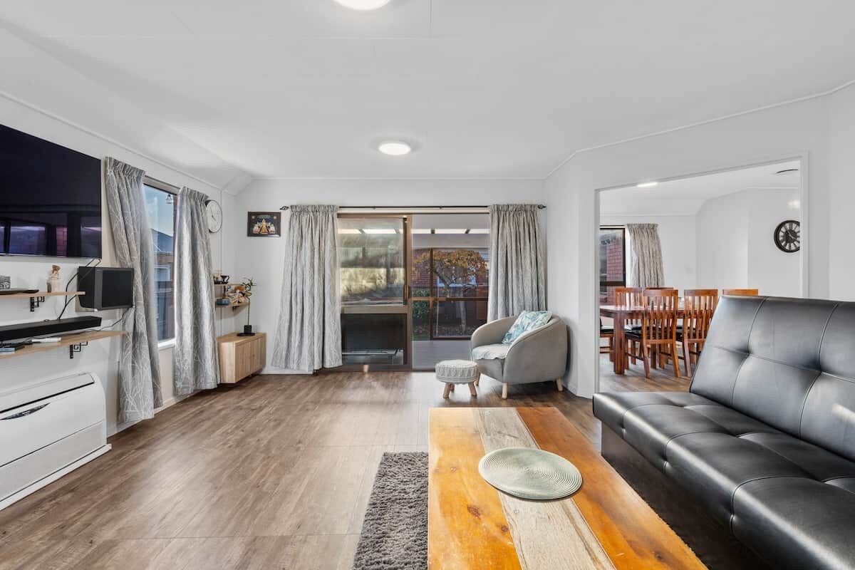 Een moderne woonkamer met een zwarte leren bank, een houten salontafel en een grijze fauteuil.