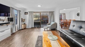 Un salon moderne avec un canapé en cuir noir, une table basse en bois et un fauteuil gris.