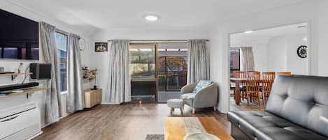 A modern living room with a black leather sofa, a wooden coffee table, and a grey armchair.