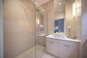 A modern bathroom with a glass-enclosed shower, a white sink, and a large mirror. - Kierbedzia Suite (Warszawa)