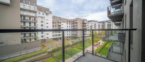Un balcon donnant sur un quartier résidentiel, avec des immeubles à plusieurs étages et un espace vert.