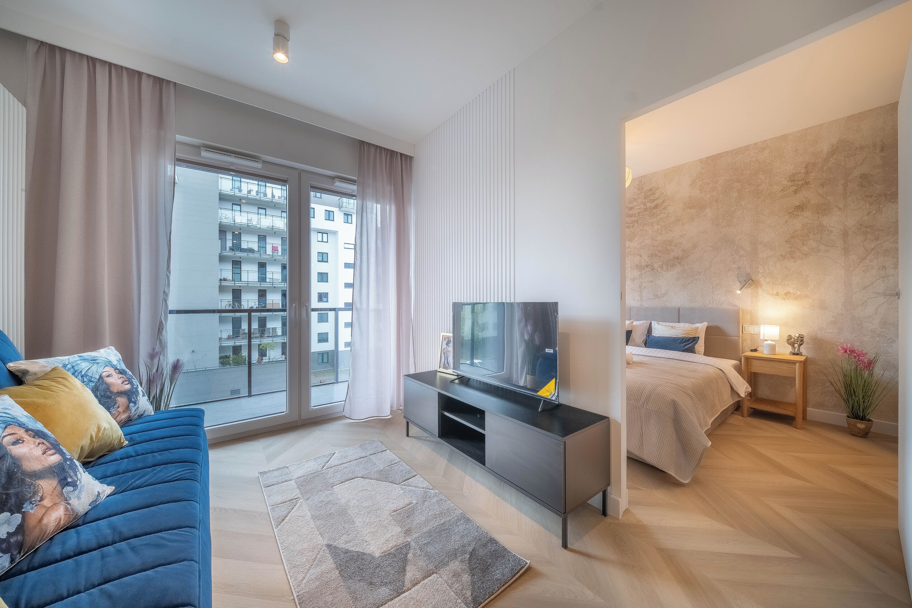 Une chambre moderne équipée d’un lit, d’une télévision et d’un balcon offrant une vue sur la ville.