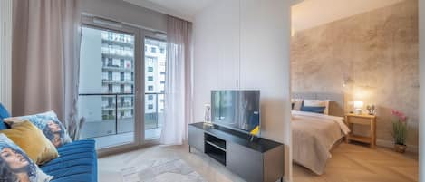 Une chambre moderne équipée d’un lit, d’une télévision et d’un balcon offrant une vue sur la ville.