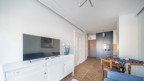A modern living room with a flat-screen TV, a white cabinet, a blue sofa, and a patterned rug. - Kierbedzia Elegant Classic Blinds, Free Parking, Mokotow, Warsaw (Warszawa)