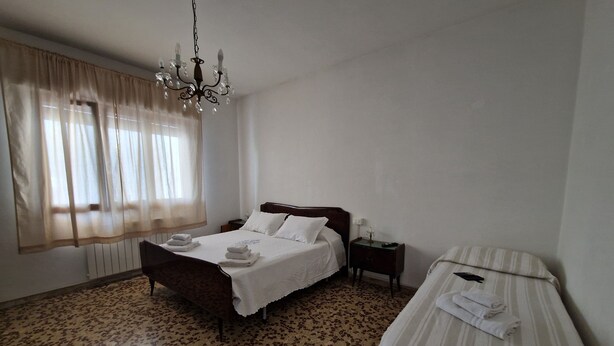 A bedroom with a bed, bedside table, and a smaller bed or couch. - CasaMiria: a cozy apartment just 5 minutes from Forte dei Marmi, with a garden (Seravezza)