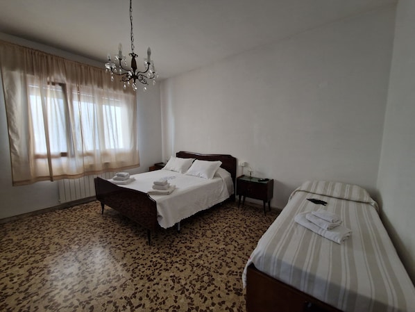 A bedroom with a bed, bedside table, and a smaller bed or couch.