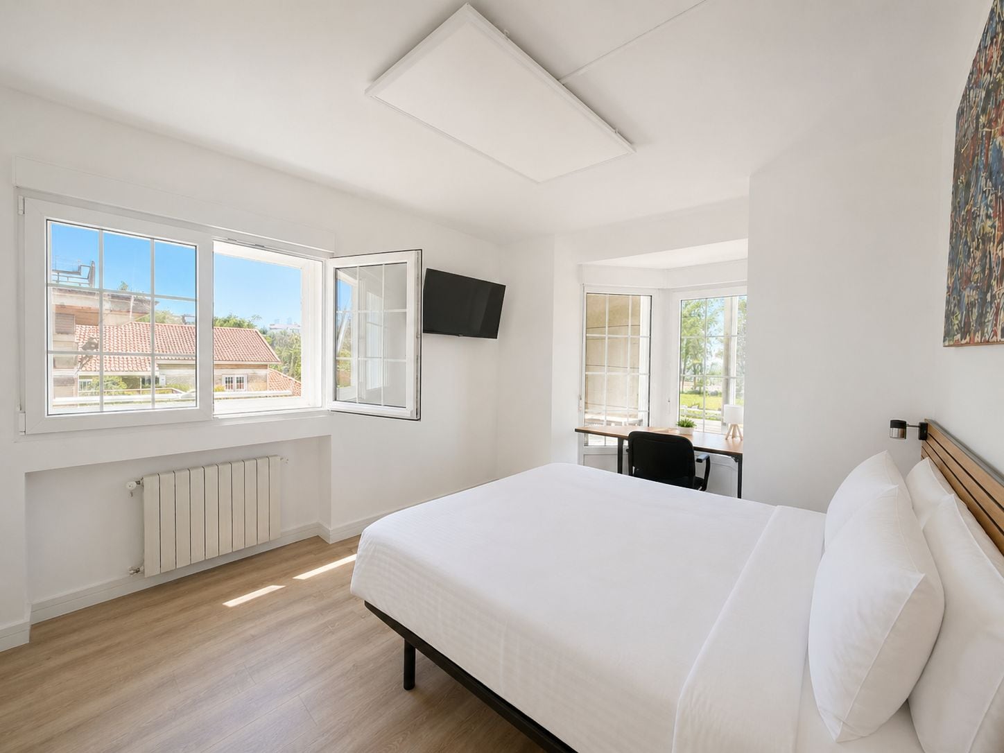 Een slaapkamer met een groot bed, een bureau en een televisie aan de muur.