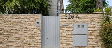 A gated entrance with a stone wall, a grey gate, and a mailbox.
