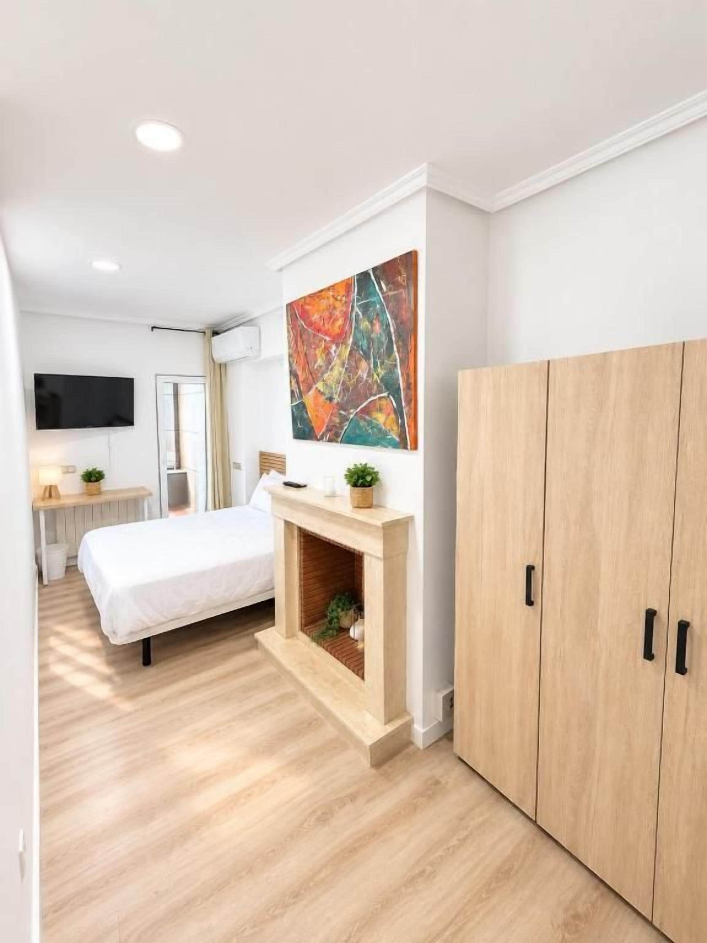 A modern bedroom with a bed, a fireplace, a television, and a wardrobe.