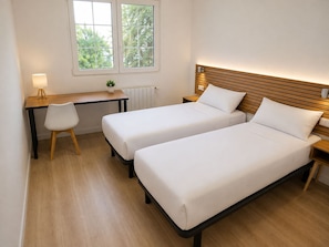 A room with two beds, a desk, a chair, and a window. - Hello Madrid Norte (Madrid)