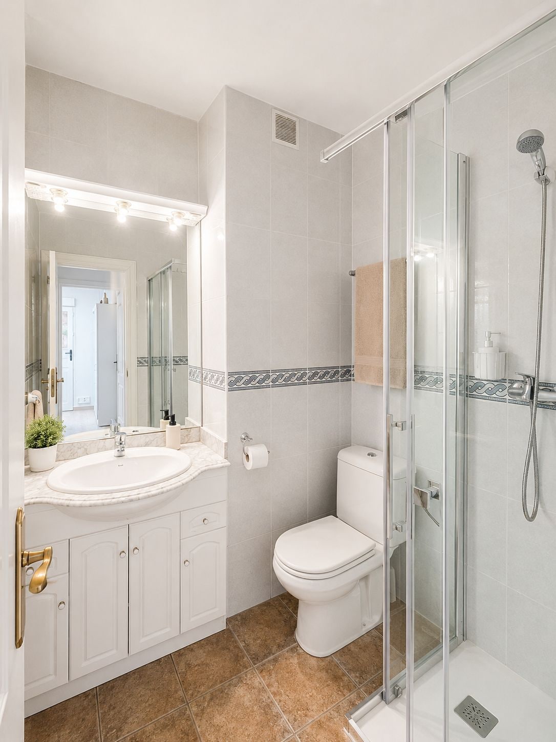 Un baño moderno con ducha acristalada, lavabo blanco y retrete.