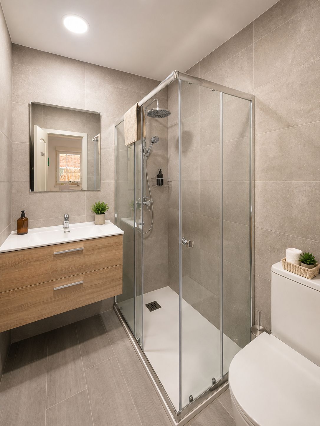 Un baño moderno con ducha envuelta en vidrio, tocador de madera y retrete.