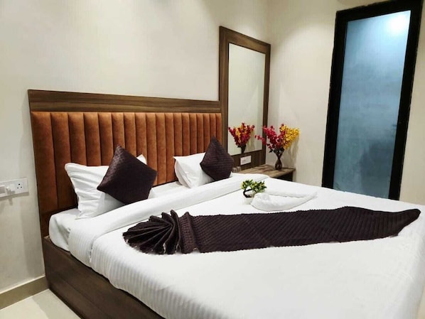 A neatly made bed with a headboard, pillows, and a blanket. - Swaraj Homestay (Varanasi)