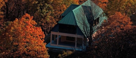 Une maison surmontée d’un toit végétalisé, entourée d’un feuillage automnal.