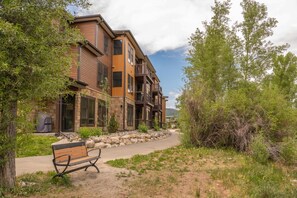 A multi-story building with a stone facade, a covered outdoor seating area, and a pathway leading to the entrance. - Upstay Lake Dillon Basecamp Mountain Trails (Silverthorne)