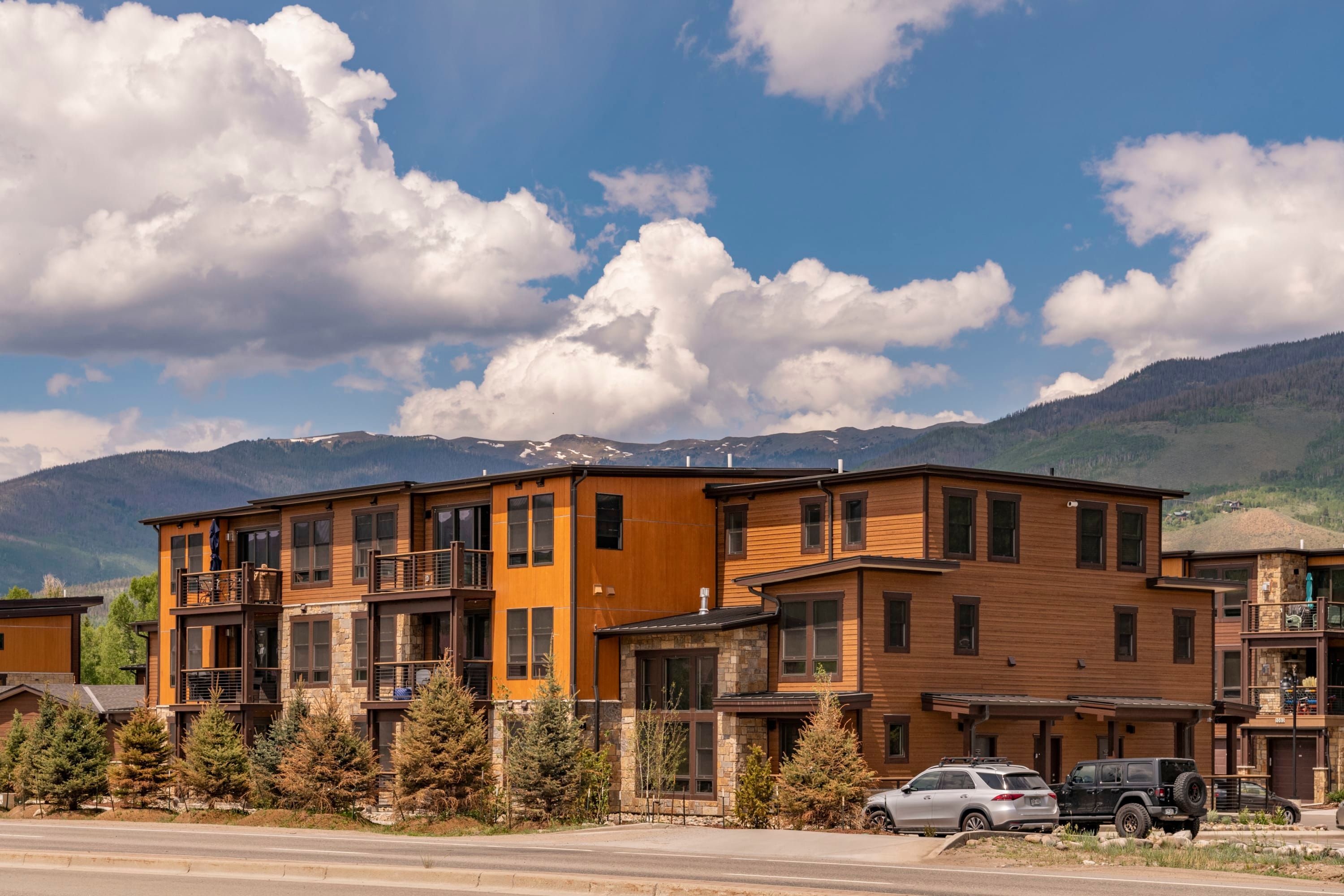 A multi-story building with balconies, a stone facade, and a view of mountains.