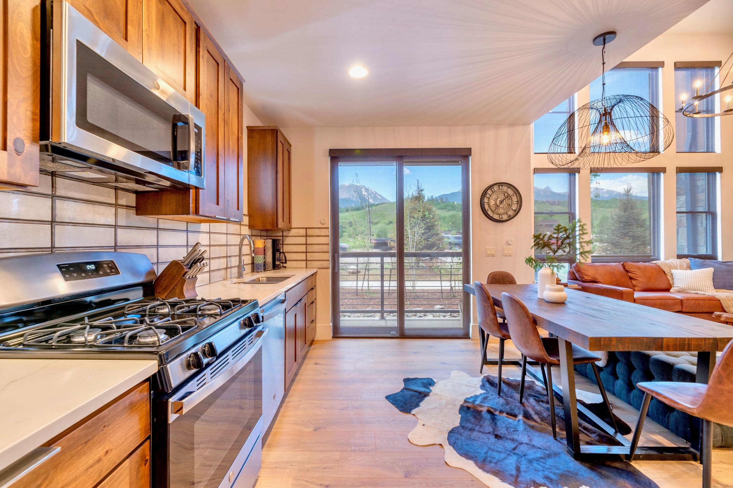 A modern kitchen with a built-in microwave, stove, and oven. There is a dining area with a wooden table and chairs.