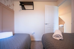 Ein Schlafzimmer mit zwei Betten, einer Tür und einem an der Wand befestigten Regal.