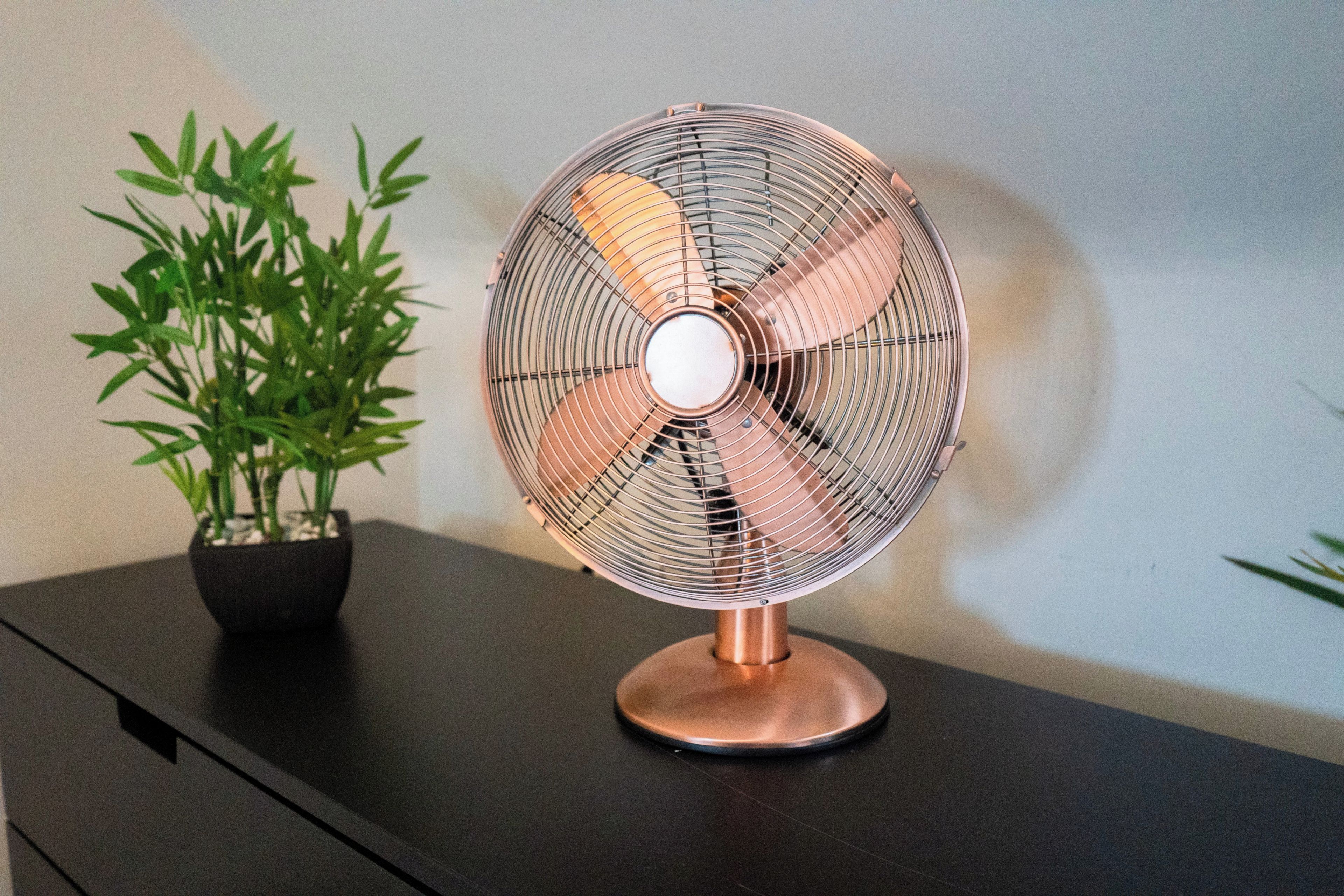 A standing fan with a metallic base on a dark surface.