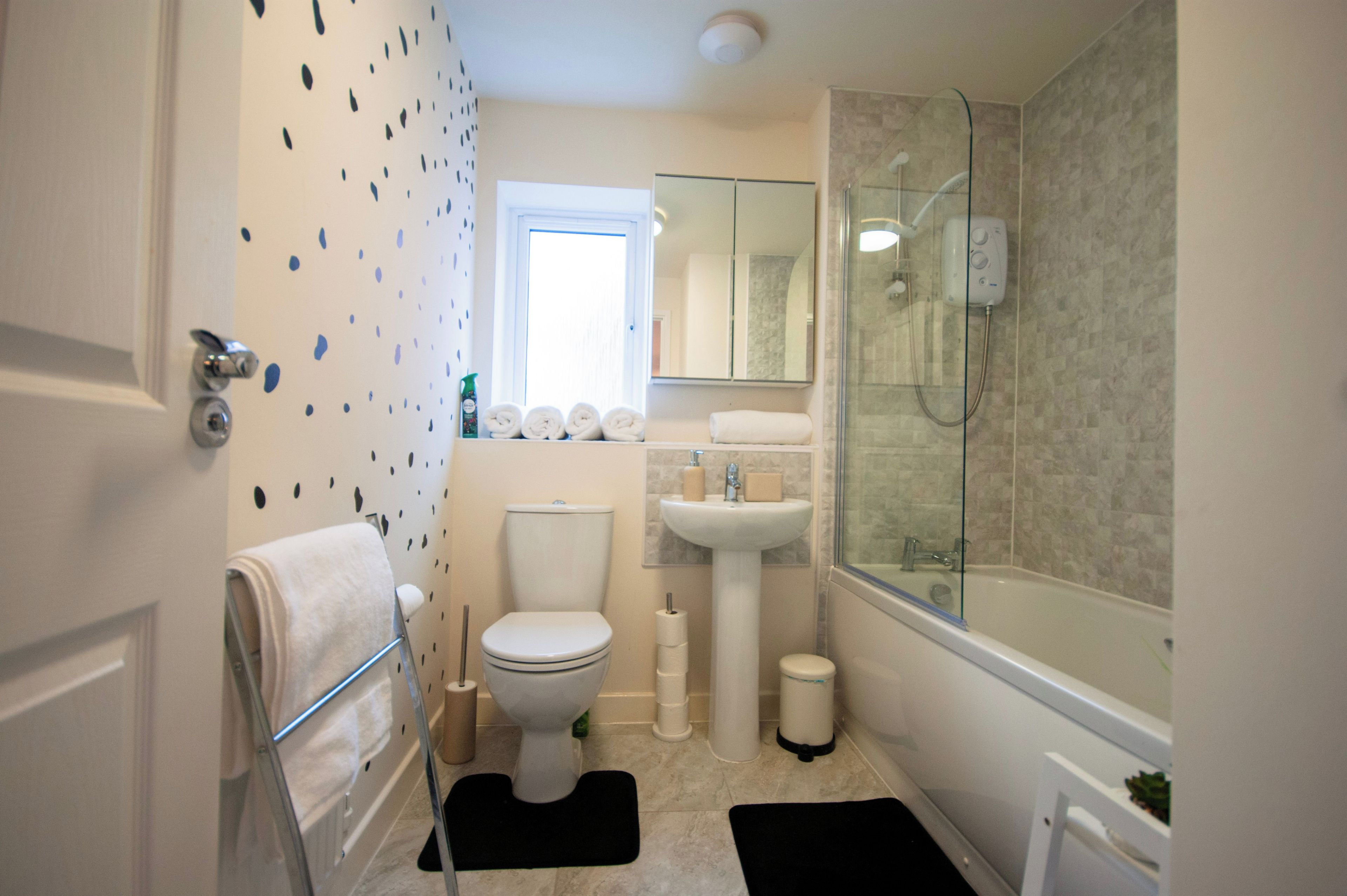 A bathroom with a toilet, sink, and shower. There are towels on a rack and a glass shower enclosure.