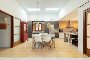 A modern kitchen with a dining area, featuring a central island, pendant lighting, and a view of the living area. - Classic Ibiza Villa · Pool + Garden + 3 Bedrooms (Islas Baleares)