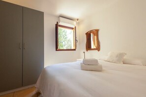 A bedroom with a bed, a wardrobe, a window, and a mirror. - Classic Ibiza Villa · Pool + Garden + 3 Bedrooms (Islas Baleares)