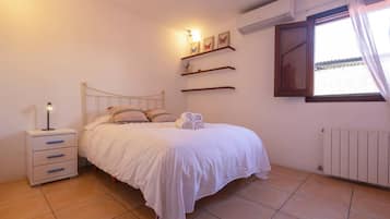 Une chambre à coucher comprenant un lit, une table de chevet, des étagères murales et une fenêtre avec des rideaux.