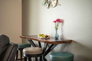 A dining area with a wooden table, a vase with flowers, and two stools. - Villa Glasswater - Lake View, Kajaks & Dock (Cape Coral)
