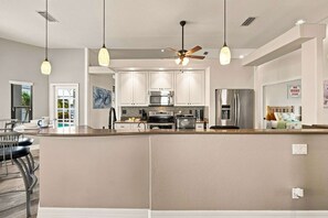 A modern kitchen with white cabinets, stainless steel appliances, and pendant lighting. - Villa Glasswater - Lake View, Kajaks & Dock (Cape Coral)