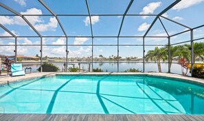 A swimming pool with a view of a lake and distant buildings. - Villa Glasswater - Lake View, Kajaks & Dock (Cape Coral)