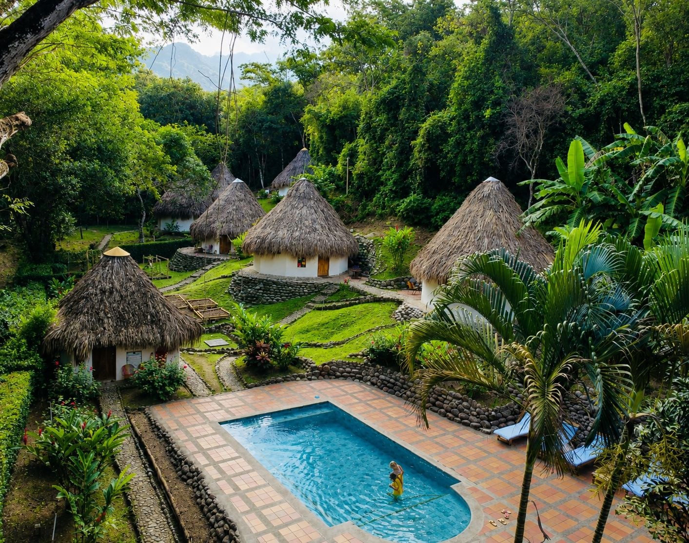 Un resort tropical con cabañas de techo de paja, piscina y abundante vegetación.