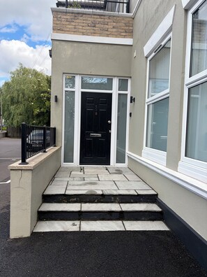 A modern building with a black door, white-framed windows, and a stone facade. - Urban Bliss (Bournemouth)