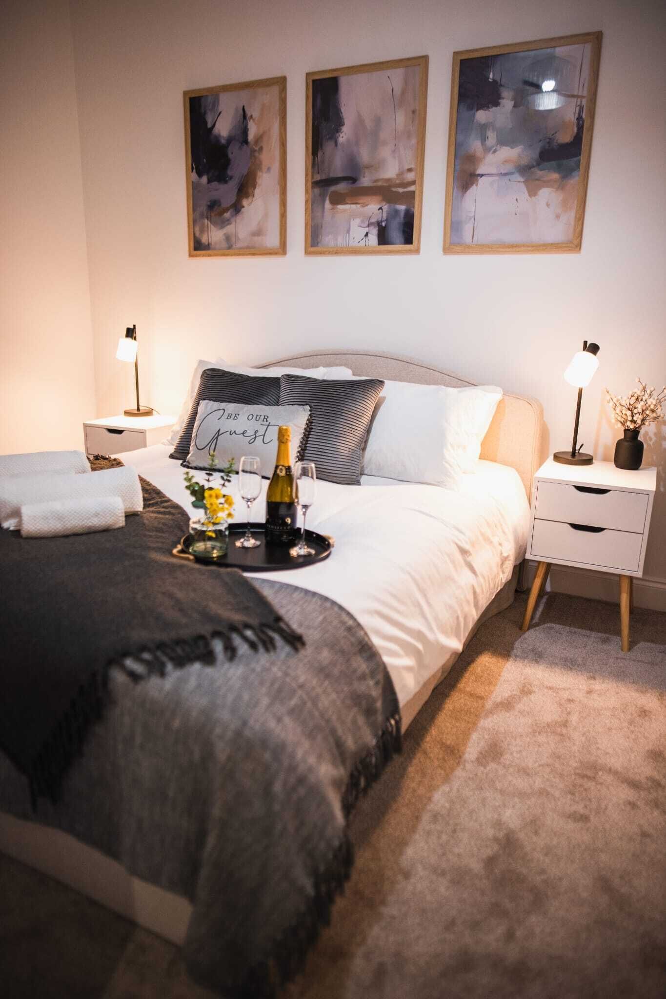 A neatly arranged bedroom with a bed, bedside tables, and abstract artwork on the wall.