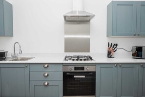 A kitchen with a stainless steel range hood, a built-in oven, and a sink with a faucet. - Urban Bliss (Bournemouth)