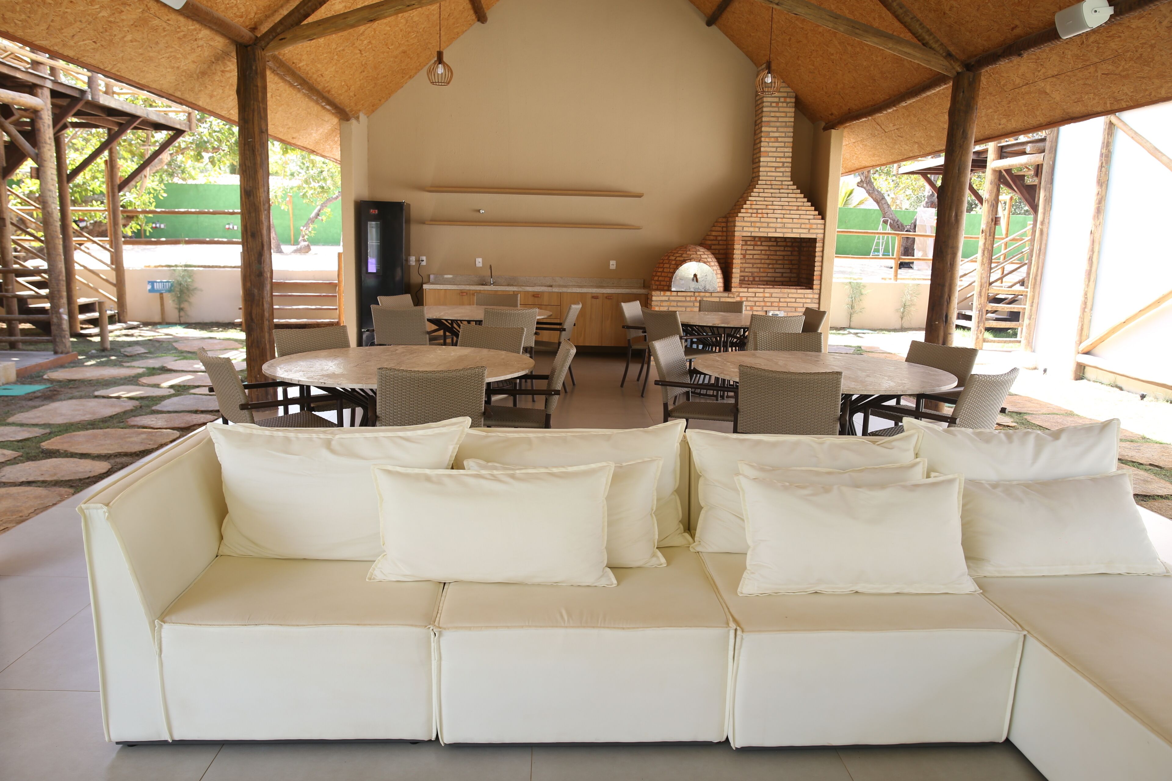 An outdoor seating area with a white sofa, wicker chairs, and a brick oven.