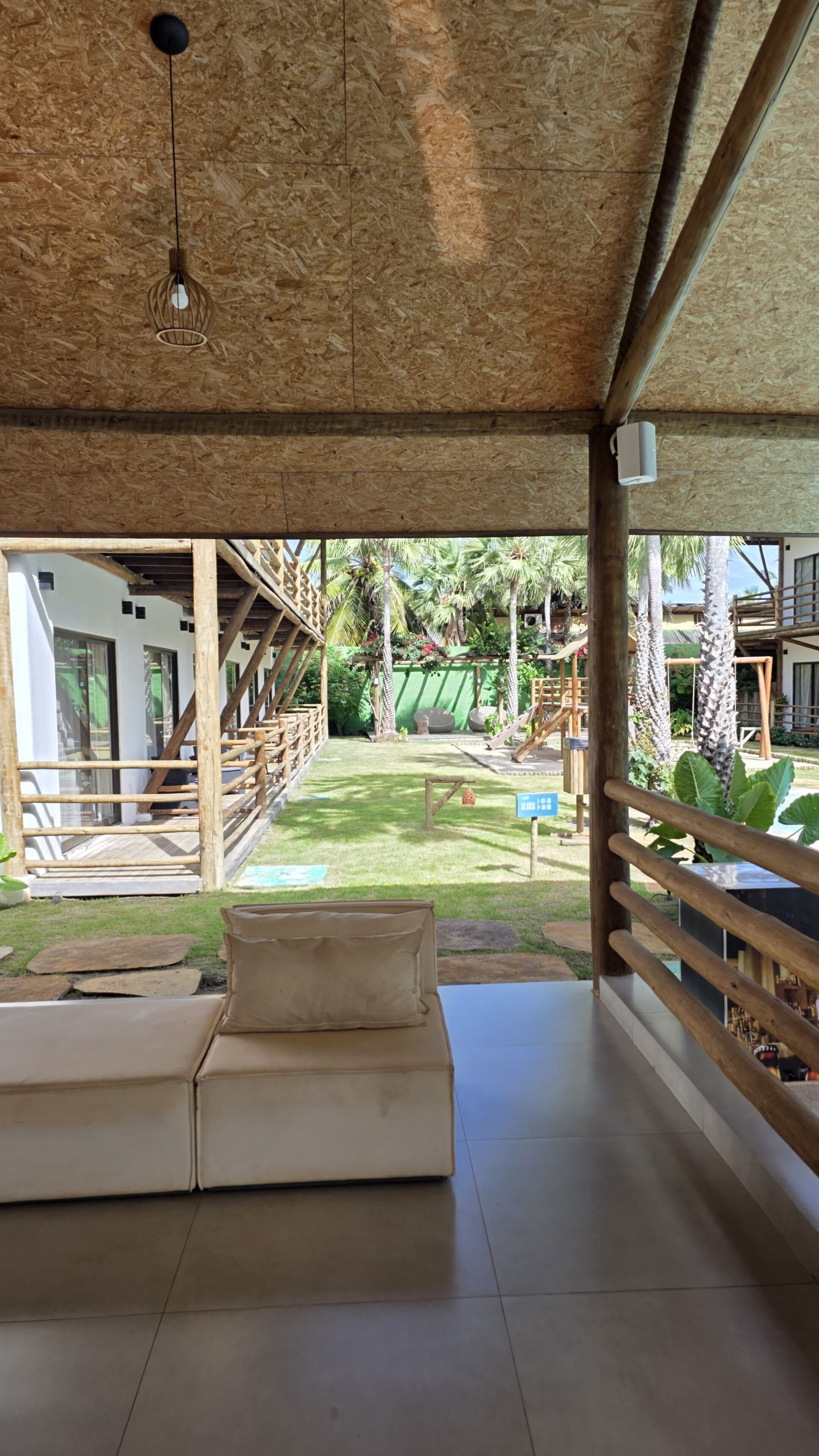 A covered outdoor seating area with a view of a pool and a wooden deck.