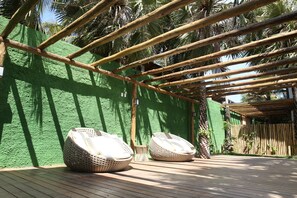 A wooden deck with two woven seating areas and a bamboo pergola structure.