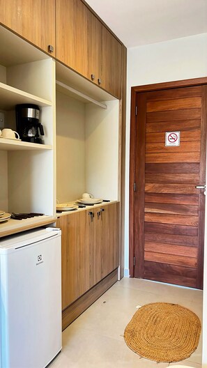 A kitchenette with a coffee maker, a refrigerator, and a door with a no-smoking sign.