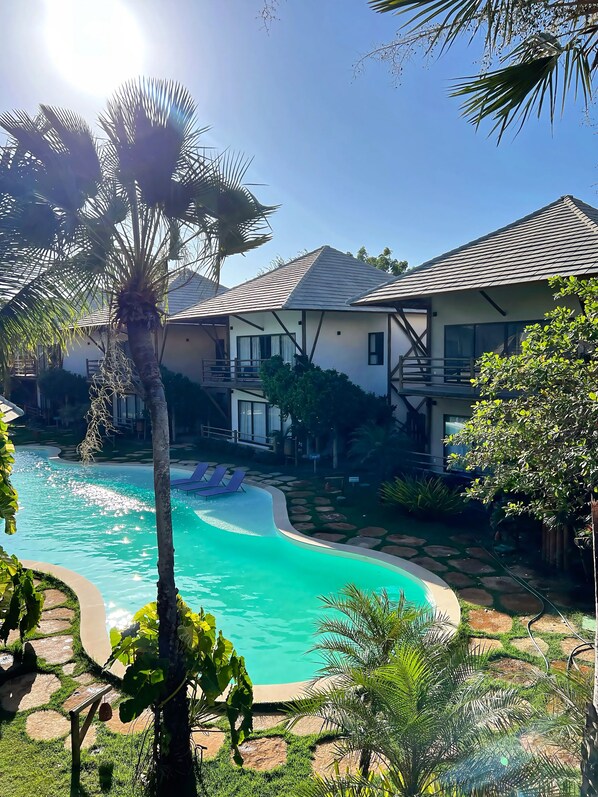 Un resort con piscina, palmeras y un edificio con balcón.