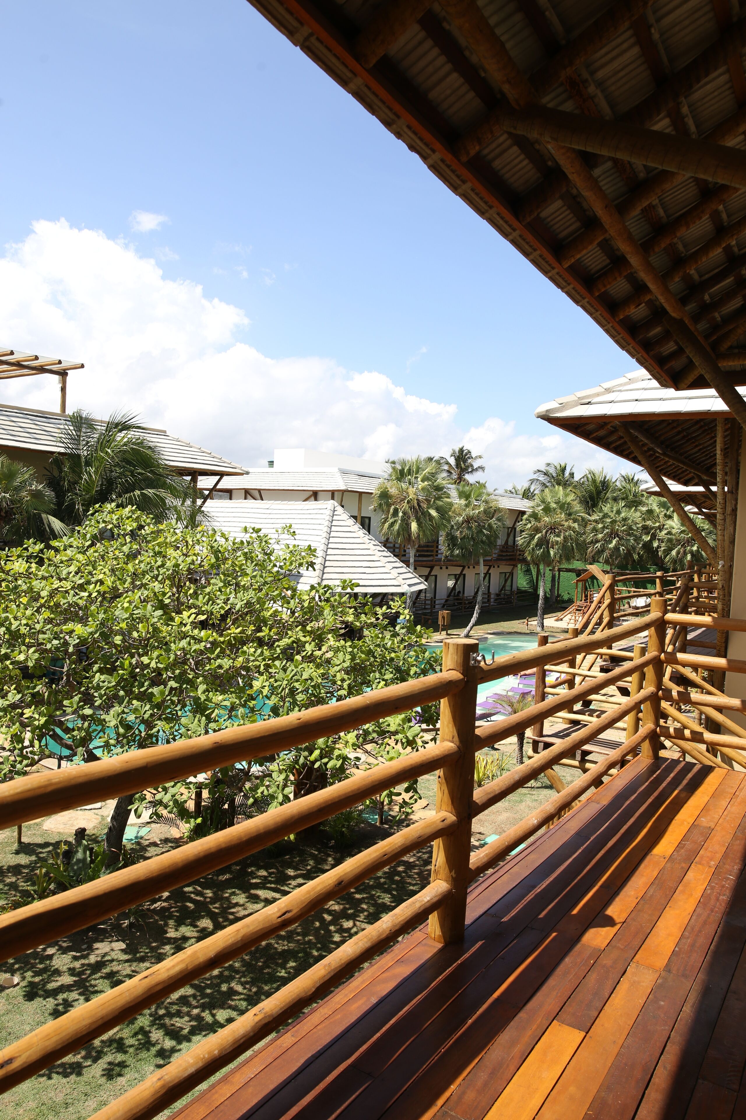 Una terraza de madera con vistas a una piscina y palmeras.