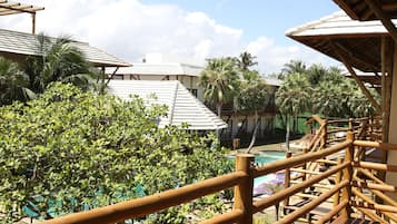Una terraza de madera con vistas a una piscina y palmeras.