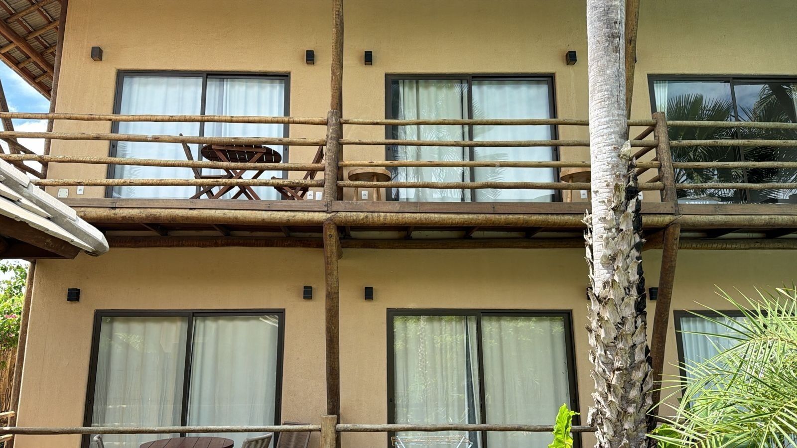 Un edificio de varios pisos con balcones, ventanas y una palmera.