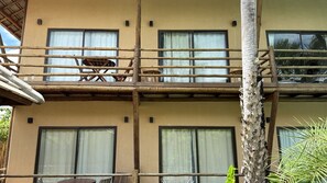 Un edificio de varios pisos con balcones, ventanas y una palmera.
