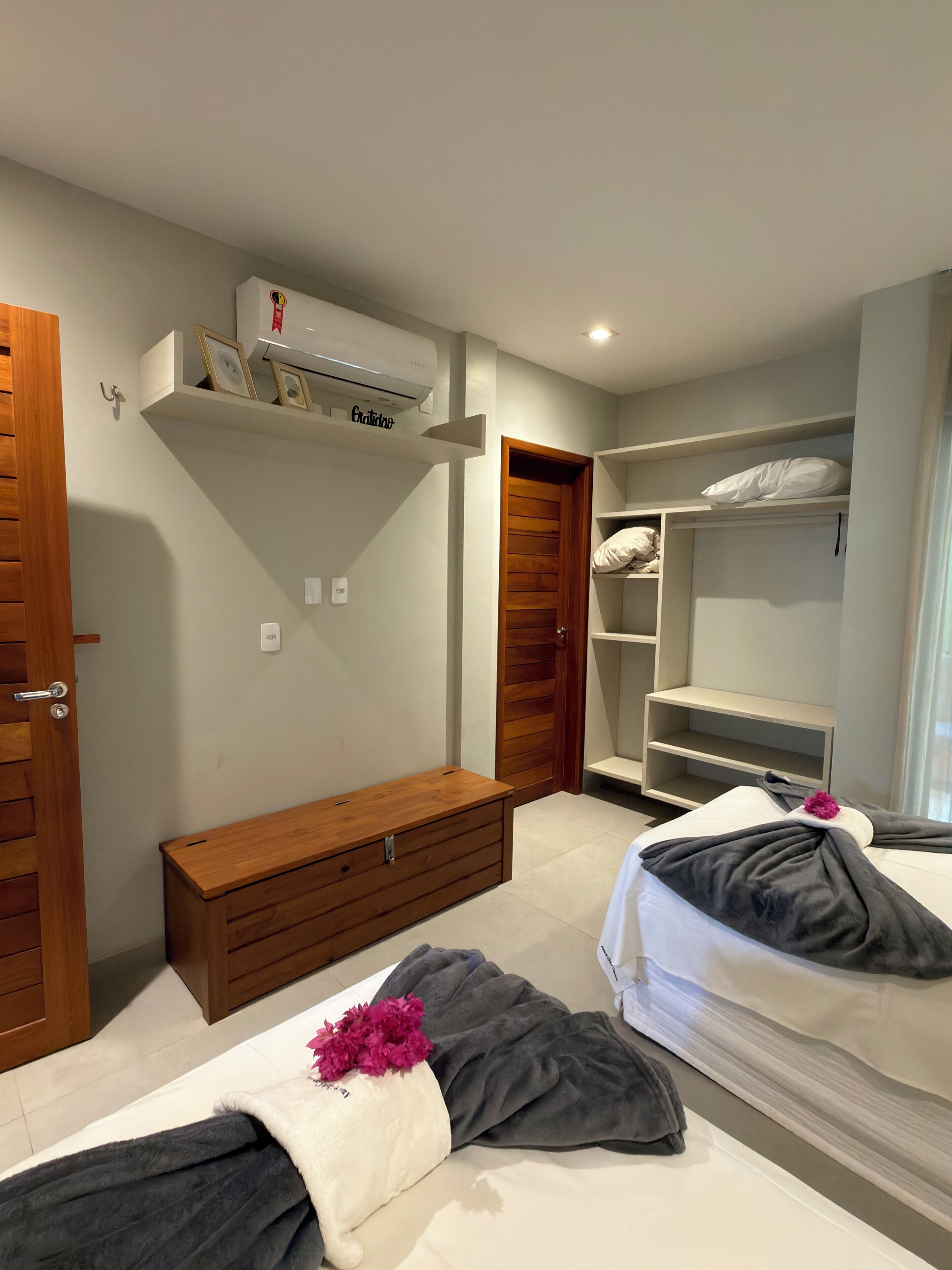 Habitación de hotel con cama, banco de madera, armario y aire acondicionado integrado.